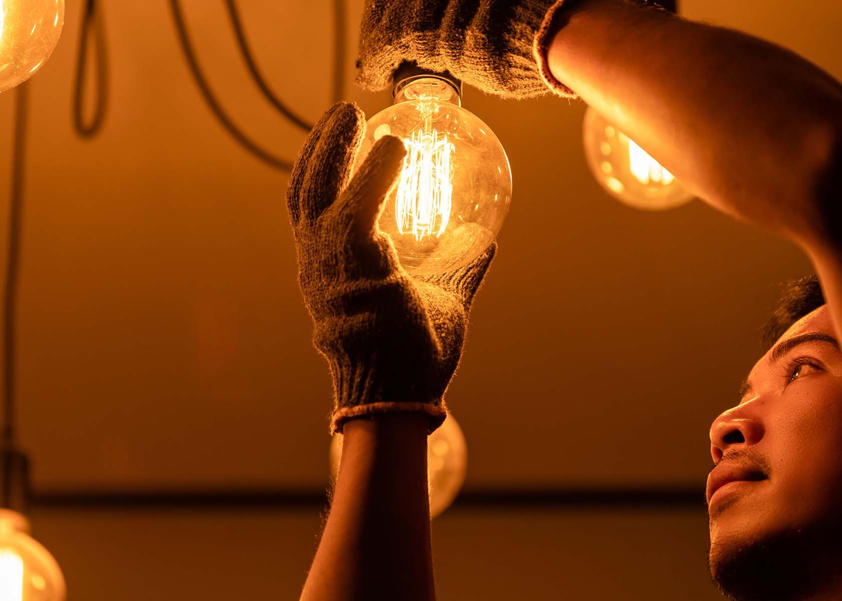 A person in gloves changing a glowing light bulb
