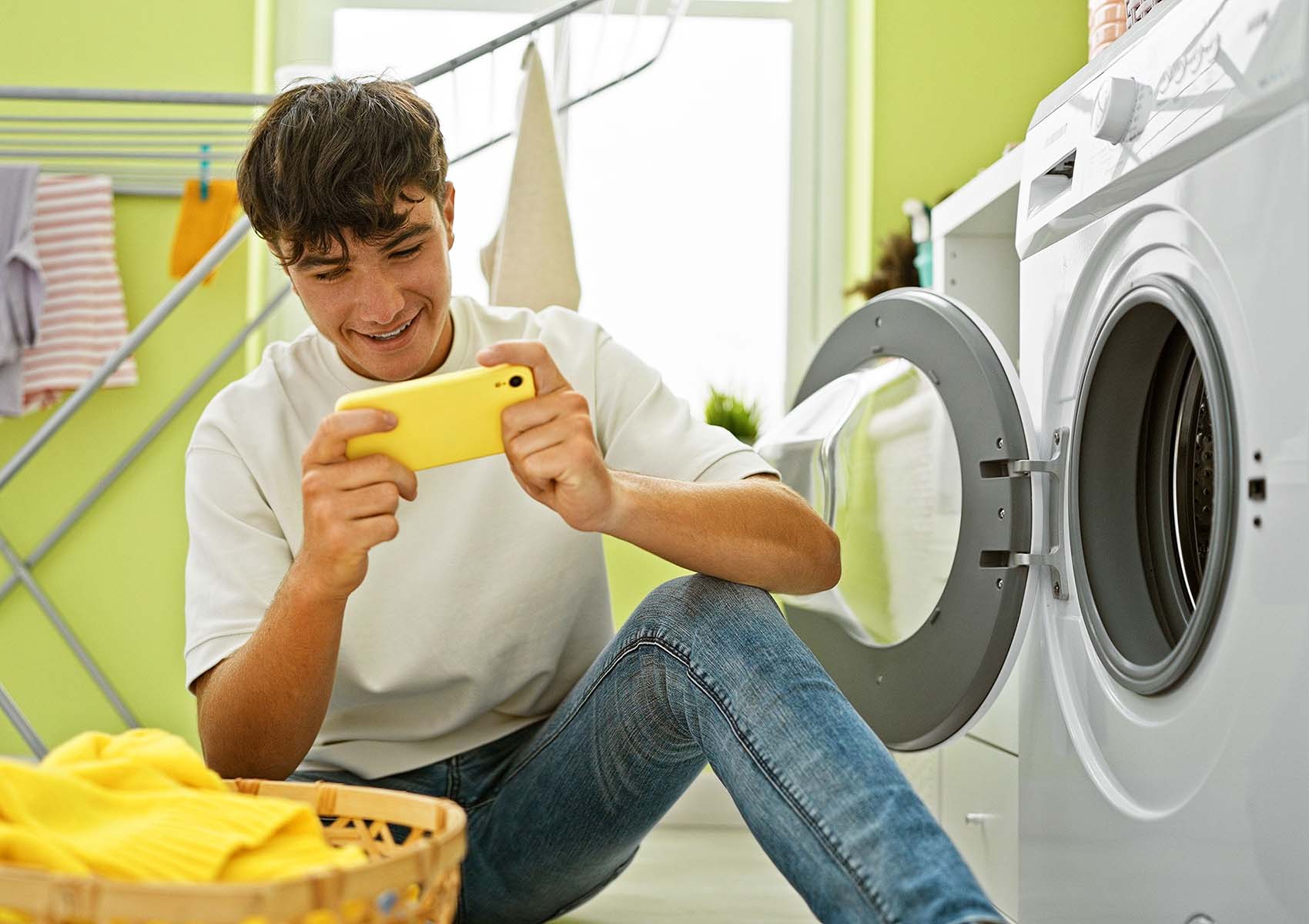 A teenager on their phone while doing laundry