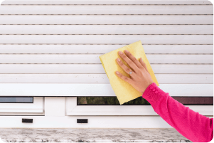 A hand cleaning blinds with a cloth.